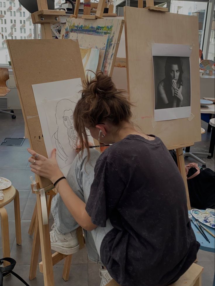 a woman sitting in front of an easel painting