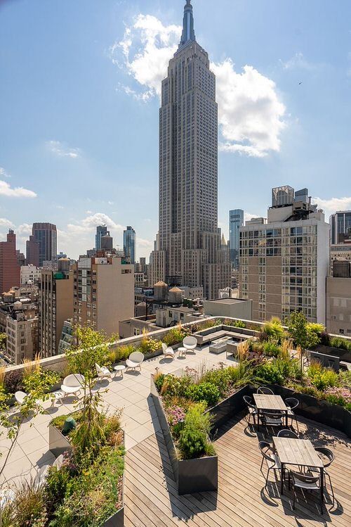 an outdoor deck with tables and chairs overlooks the city's tall skyscraper building