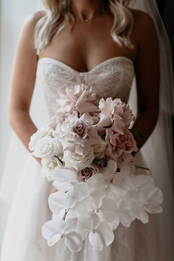 a woman in a wedding dress holding a bridal bouquet with pink and white flowers