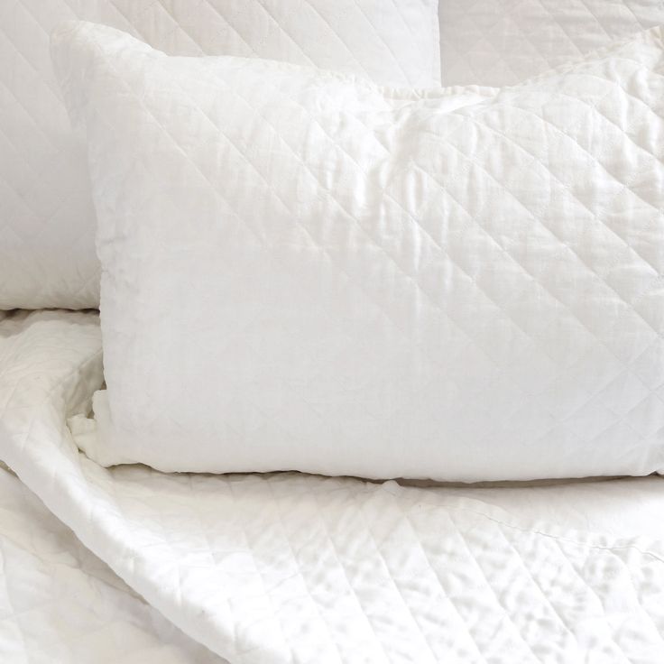 two white pillows sitting on top of a bed