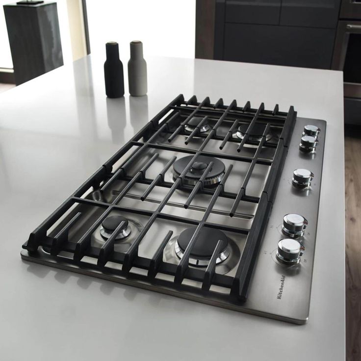 a stove top with several burners and knobs on it's side in a kitchen