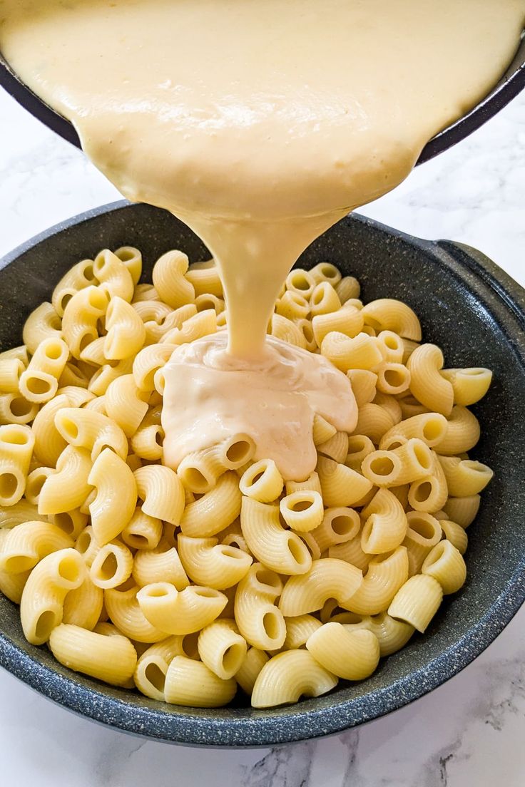 macaroni and cheese being poured into a skillet