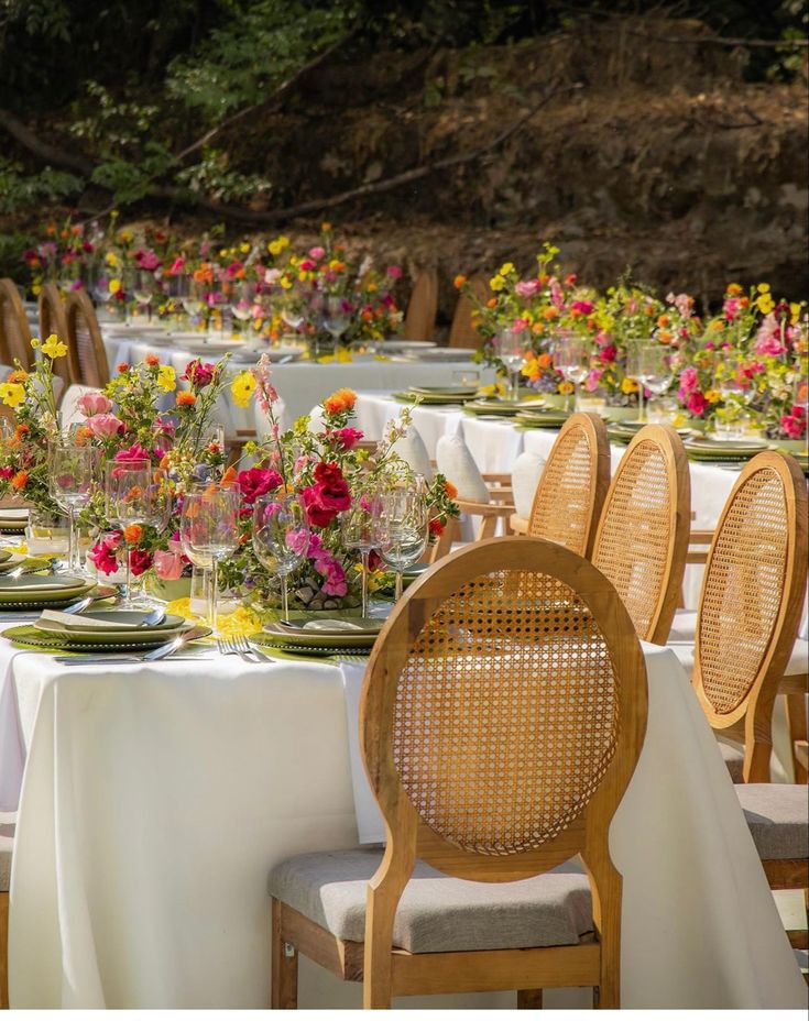 a table set up with flowers and plates on it for an outdoor dinner or party