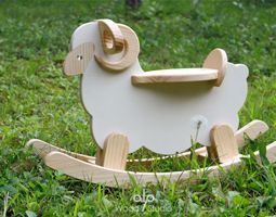 a wooden toy sheep sitting in the grass