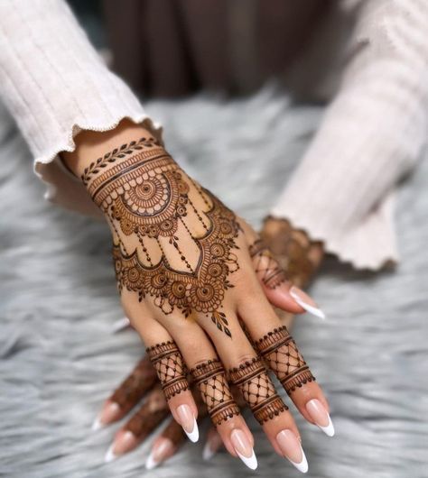 a woman's hand with henna tattoos on it and her hands painted white