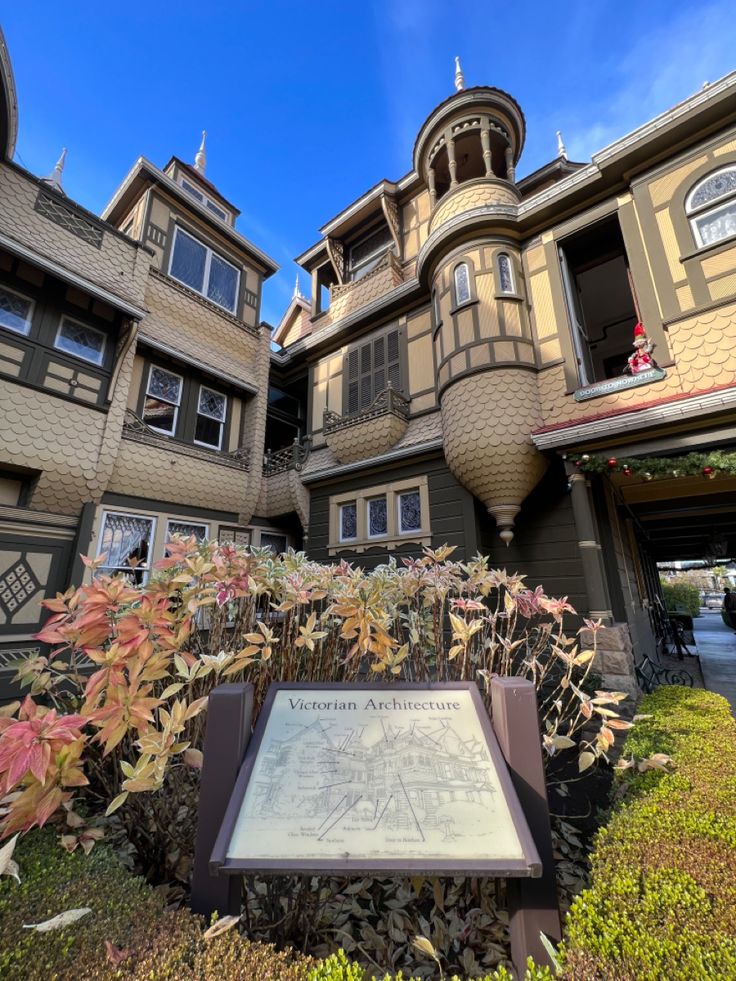 the exterior of an apartment building with a plaque in front of it and flowers growing on the ground