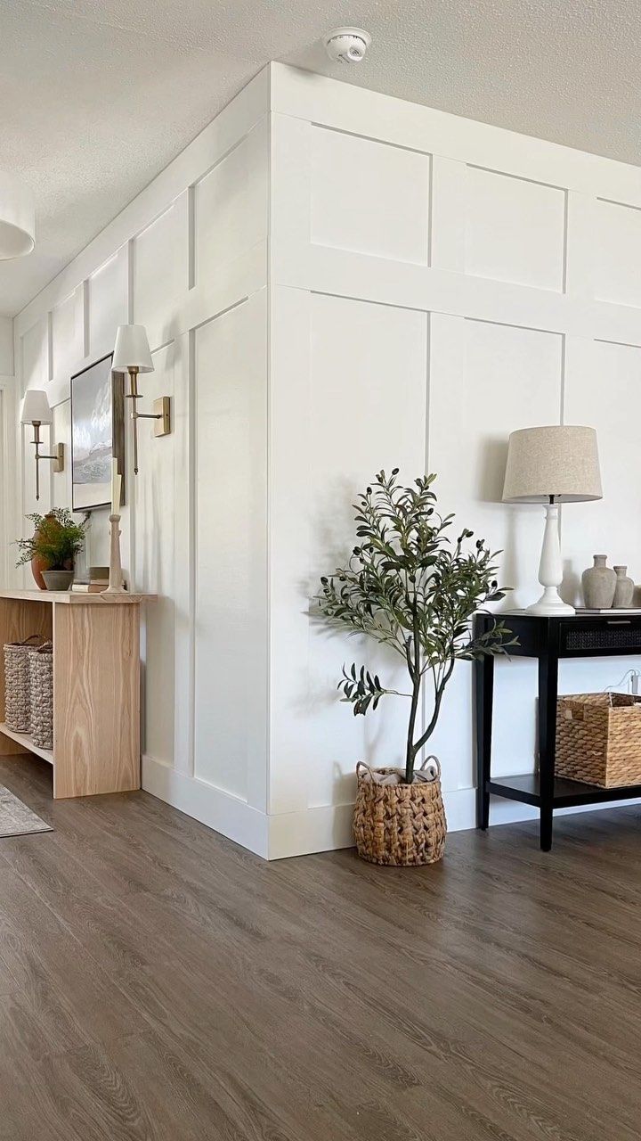 a living room with white walls and wood flooring is pictured in this image, there are two lamps on either side of the wall