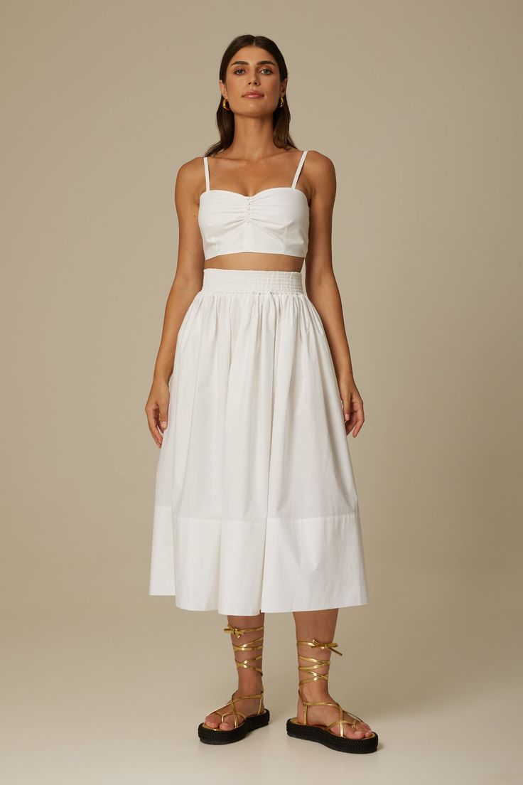 The Sofia midi skirt in crisp white is cut from Italian organic cotton poplin in a breezy full shape and features a comfortable elasticized waist, side seam pockets and a concealed zipper. Wear yours with the matching Daria bustier or one of our signature sweaters. Fit: Bianca, our model is 5.8” or 1.77 m tall and wears size 1. The skirt measures approximately 32" (80cm) long. Content: 100% organic cotton poplin. Care instructions: - For easy care, professional wash and fold is recommended. - Ma Summer Gathered Waist Midi Skirt, Summer Midi Skirt With Gathered Waist, White Cotton Midi-length Bottoms, White Cotton Midi Bottoms, White Bottoms With Gathered Waist For Spring, White Cropped Bottoms For Daywear, Chic Cropped White Skirt, White Bottoms With Gathered Waist For Summer, White Pleated Waist Bottoms For Day Out