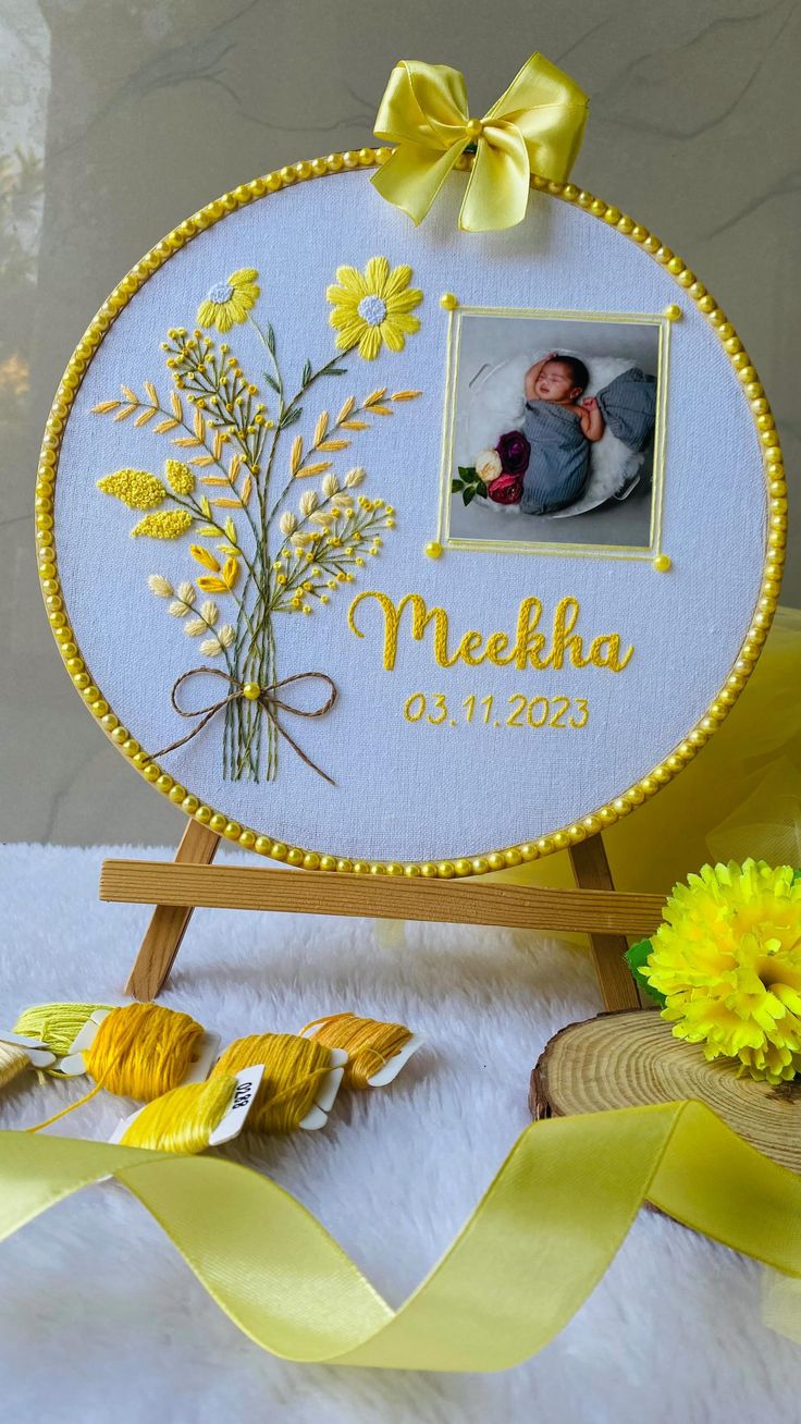 a baby's photo frame with yellow flowers on it and a ribbon around it