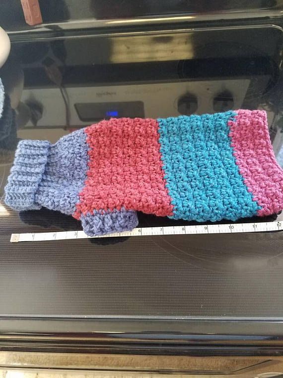 a crocheted dish cloth sitting on top of an oven door handle with a measuring tape