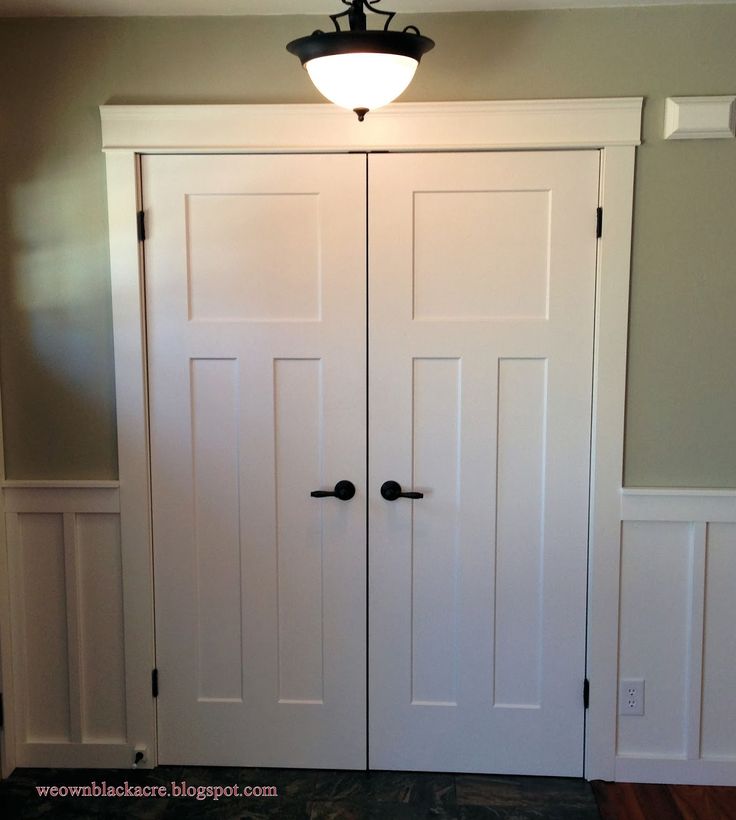 two white closets with black handles and knobs on the doors in a room