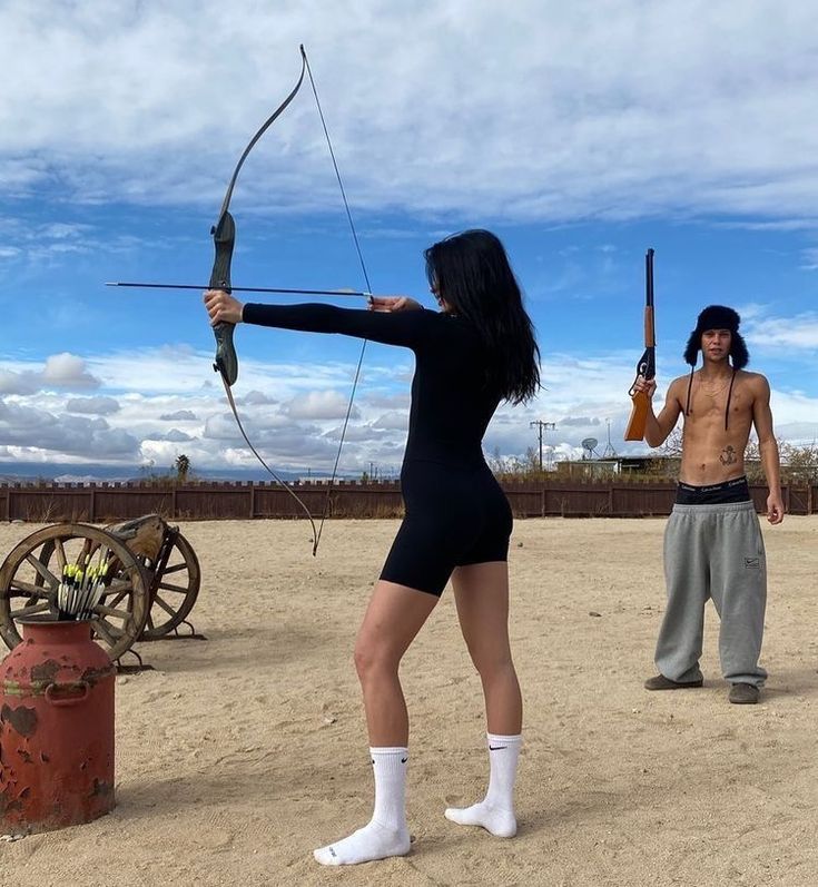 a woman in a black bodysuit holding a bow and arrow