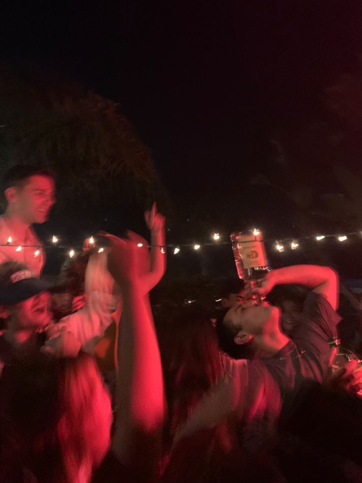 a group of people standing around each other at a concert with their hands in the air