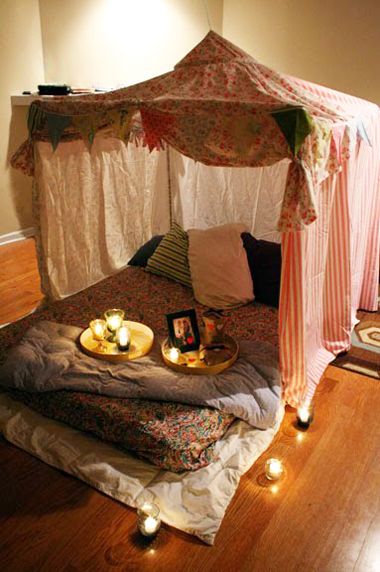 a bed that has candles on it in the middle of a room with a canopy over it