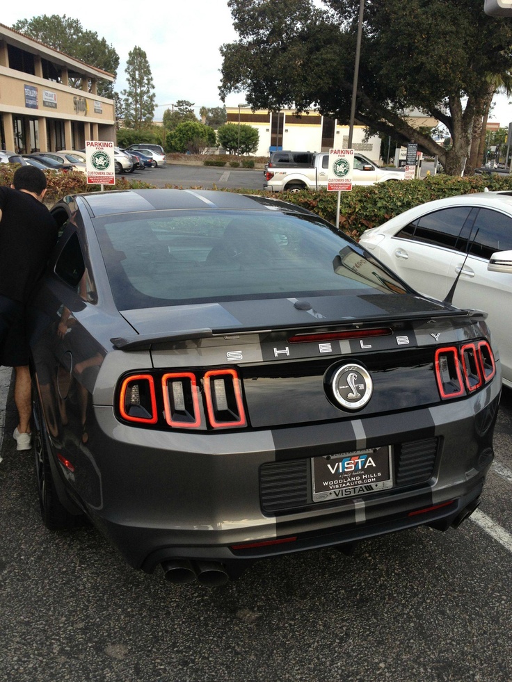 a car parked in a parking lot with its door open and people looking at it