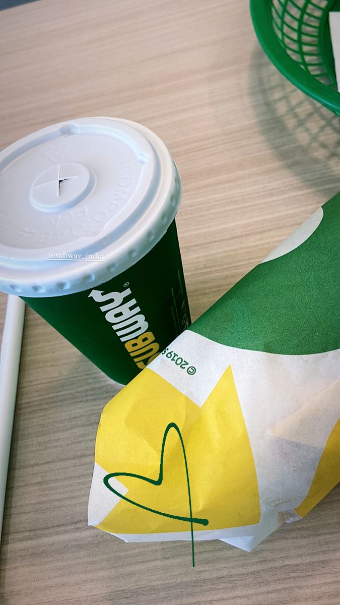 a green and white paper bag next to a starbucks cup