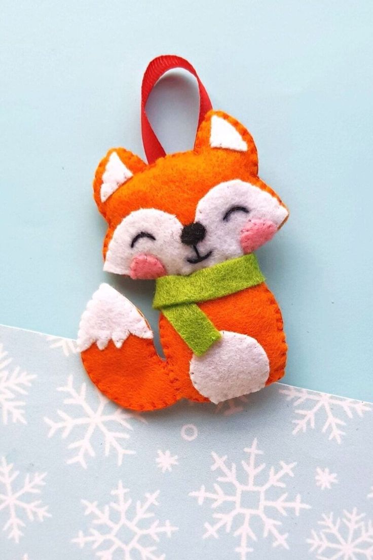 a felt fox ornament hanging on a blue background