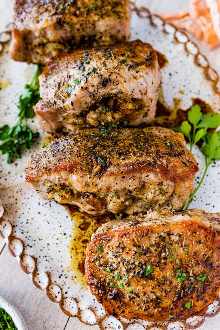 three pieces of meat sitting on top of a white plate next to some parsley