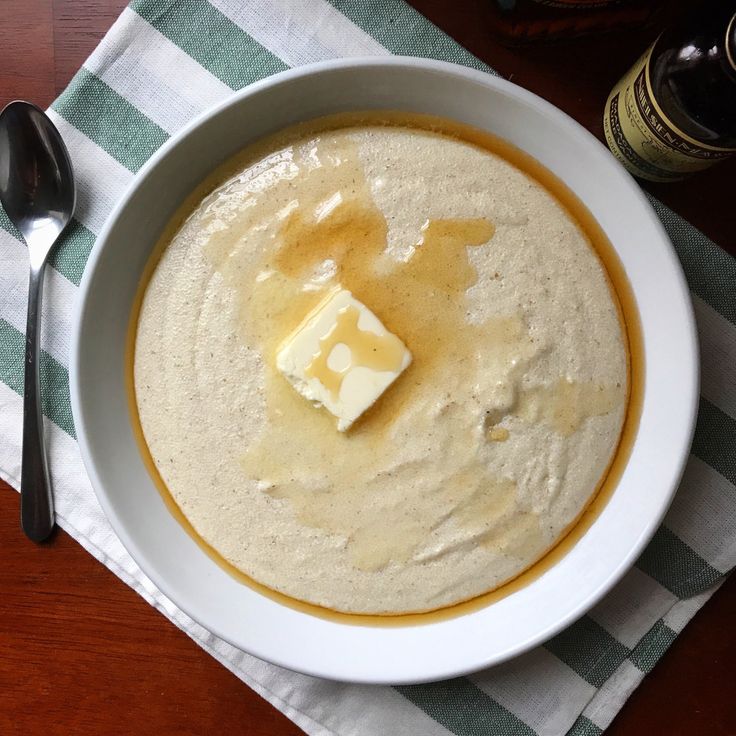 a white bowl filled with soup and cheese on top of a green and white napkin