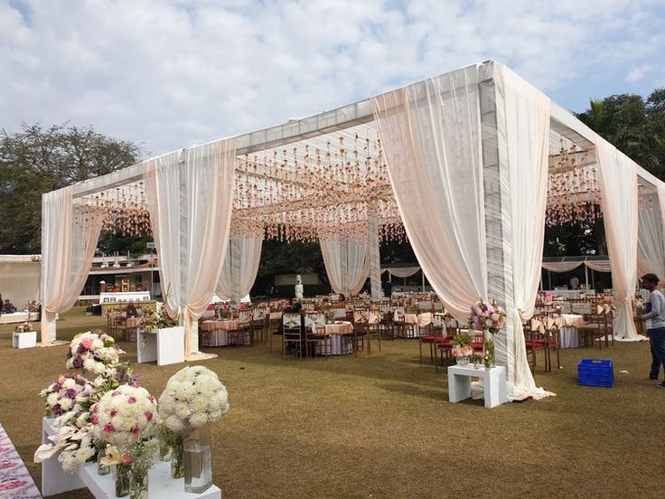 an outdoor wedding venue set up with white drapes and flowers on the ground,