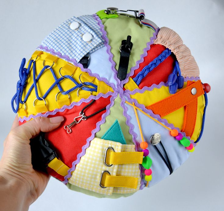 a hand holding a multicolored purse made out of cloths and other items