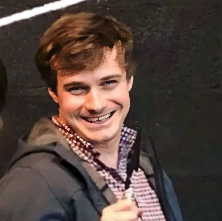 a young man with a backpack smiles at the camera