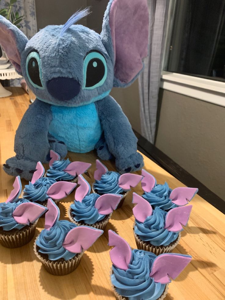 a stuffed animal next to some cupcakes on a table