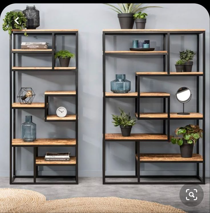 two shelving units with plants and bookshelves on them in front of a wall