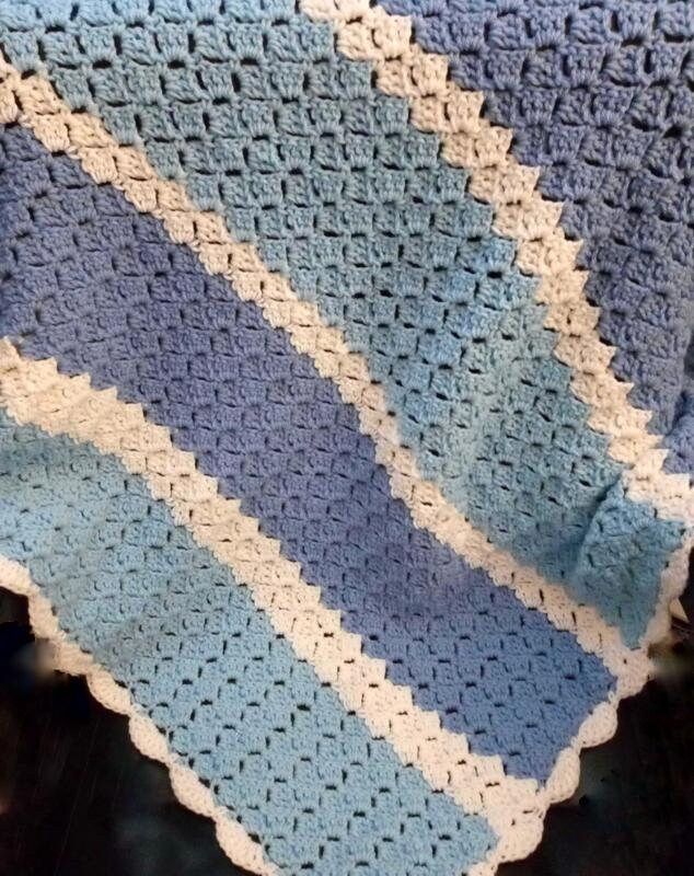 a blue and white crocheted blanket sitting on top of a chair