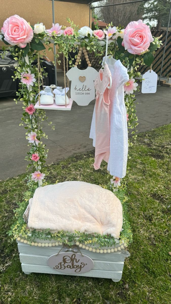 a baby's cradle with pink flowers and greenery on it in the grass