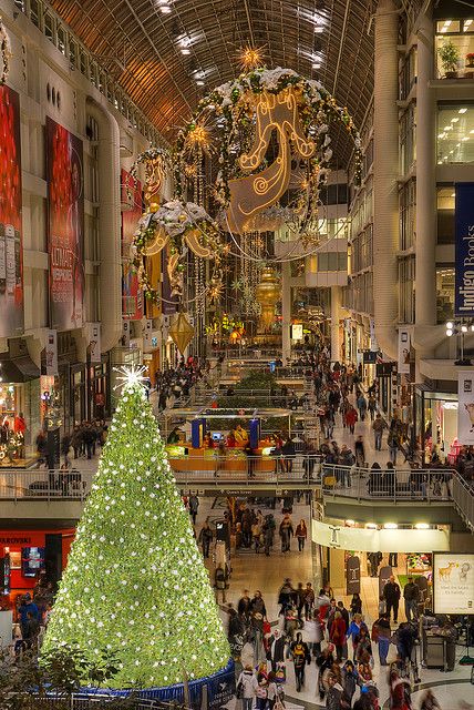 a large christmas tree in the middle of a shopping mall with lots of people walking around