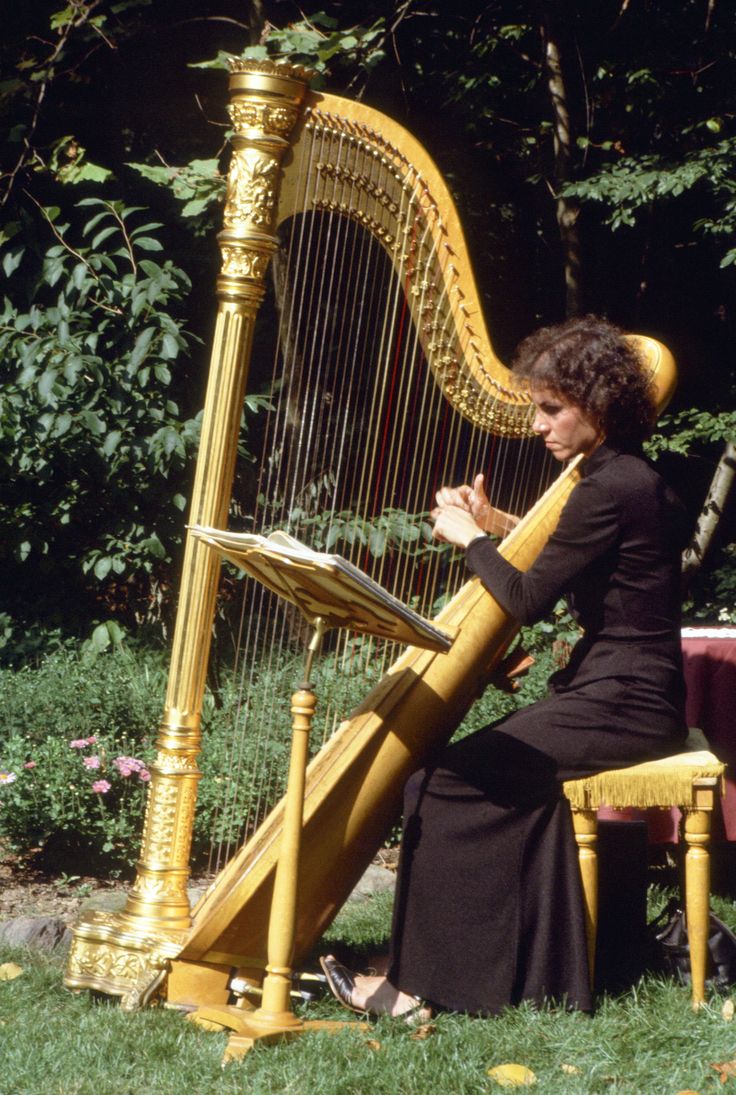 a woman sitting on top of a chair next to a golden harp