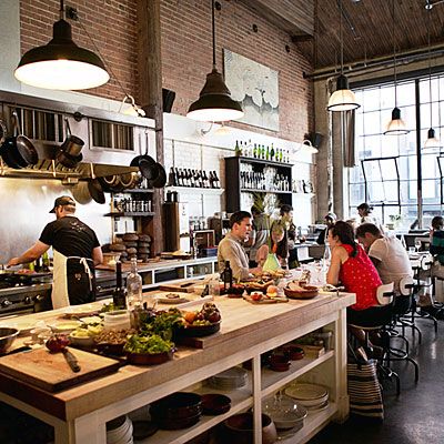 a group of people sitting at a table in a restaurant with lots of food on the counter