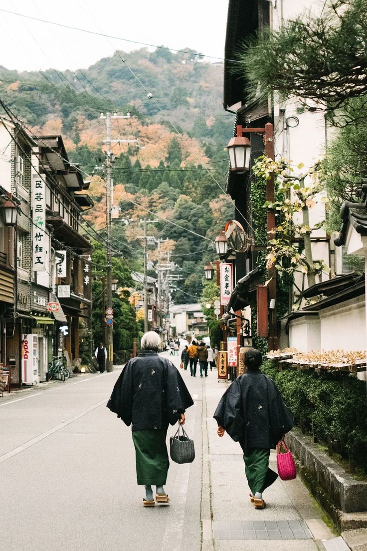 two people walking down the street carrying bags