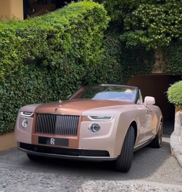 a rolls royce parked in front of some bushes