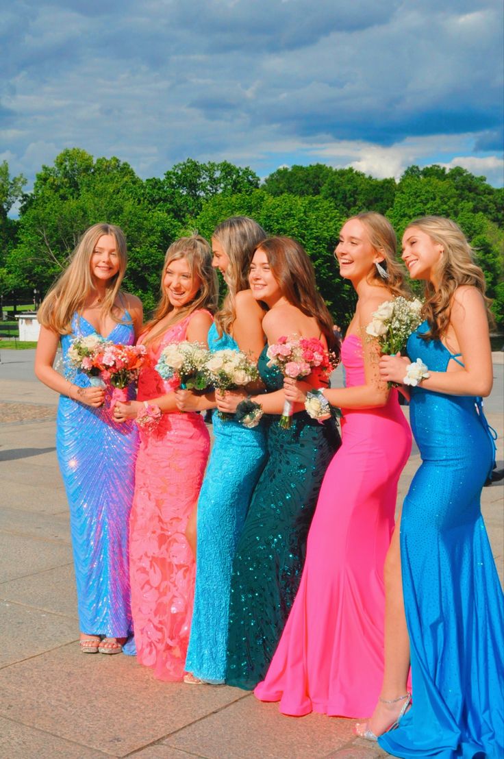 a group of women standing next to each other in long dresses and holding bouquets