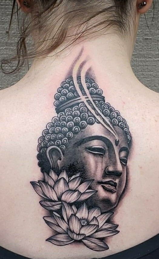 the back of a woman's neck with a buddha head and lotus flowers on it