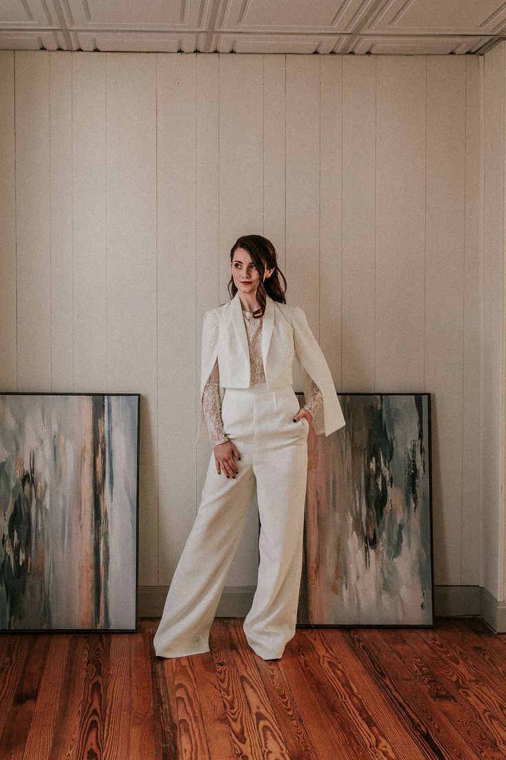 a woman standing in front of two paintings on the floor with her hands on her hips