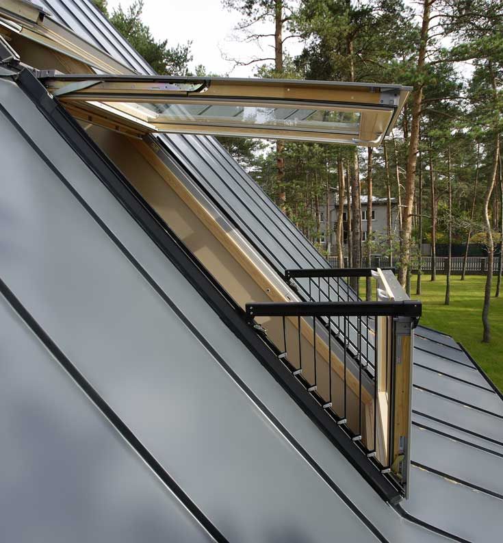 an angled window on the side of a building with grass and trees in the background