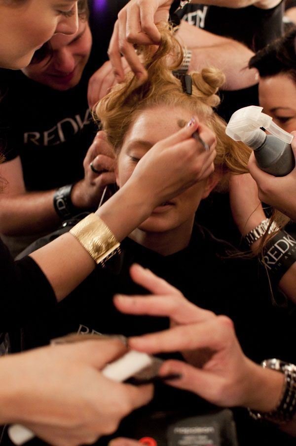 a group of people standing around each other cutting their hair