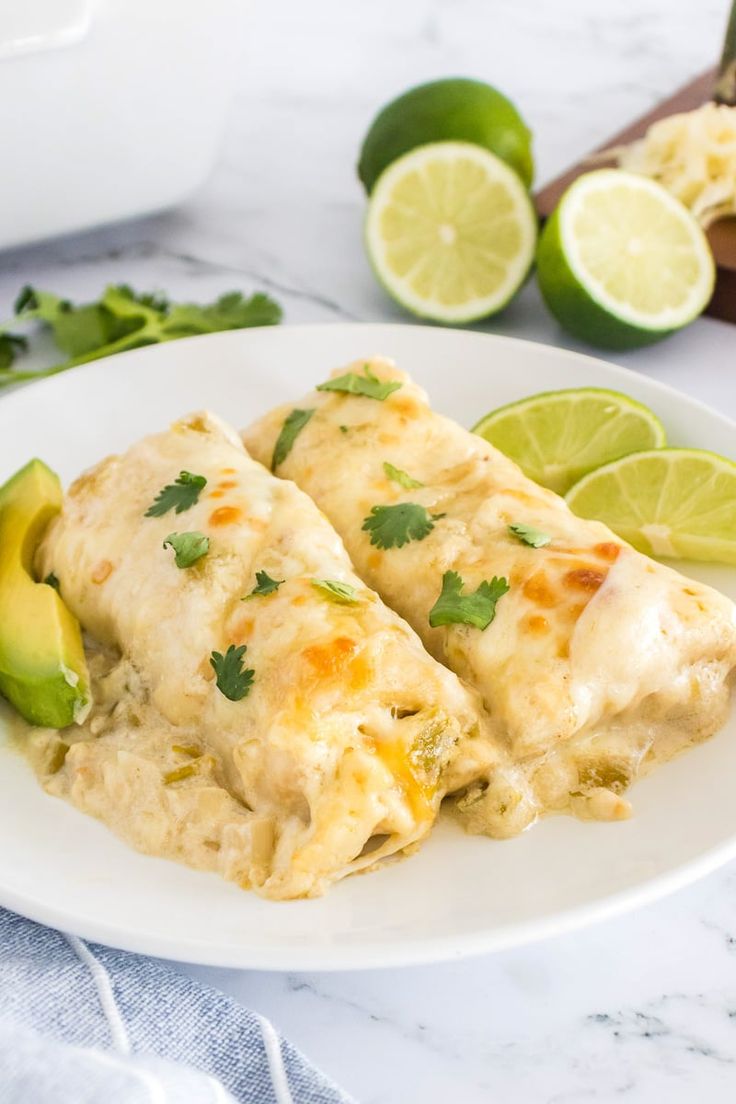 two enchiladas on a white plate with limes