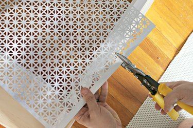 a person cutting paper with scissors on top of a piece of plywood and wood