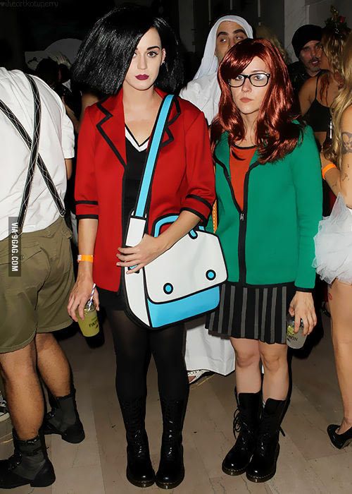 two women dressed in costumes standing next to each other at a costume party, one holding a purse and the other wearing glasses