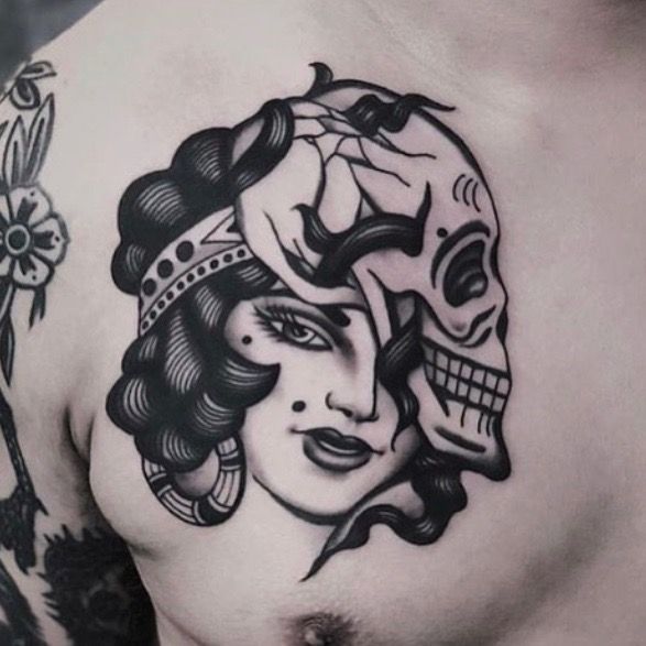 a woman's chest with a skull and flower tattoo design on her left side