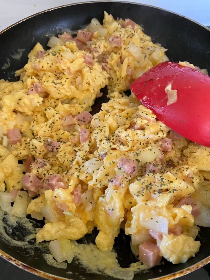 an omelet is being cooked in a skillet with a red spatula