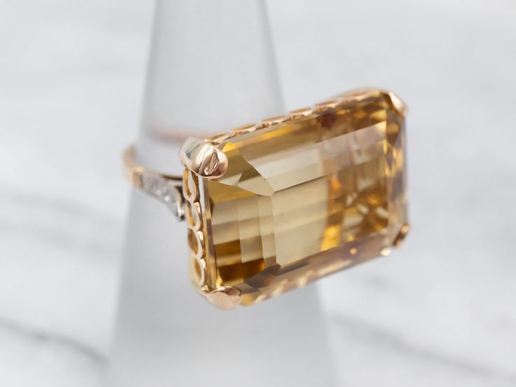 What a beauty! The centerpiece of this lushly shaded ring is the bright, golden-hued citrine that we've set at the center. Although filled with neutral tones that will go with anything, this amazing mounting is filled with color and light sparkling from the twinkling diamonds!Metal: 18K Yellow and White GoldGem: Citrine 27.20 Carats Gem Measurements: 21.7 x 15.8 mm, Emerald CutAccents:� 6 Diamonds totaling .08 Carats, SI-I in Clarity, G-I in ColorRing Size: 5.75 Diamond Cocktail Ring, Color And Light, Filigree Pendant, Diamond Cocktail Rings, Rose Gold Band, White Gold Band, Diamond Drops, Vintage Turquoise, Color Ring