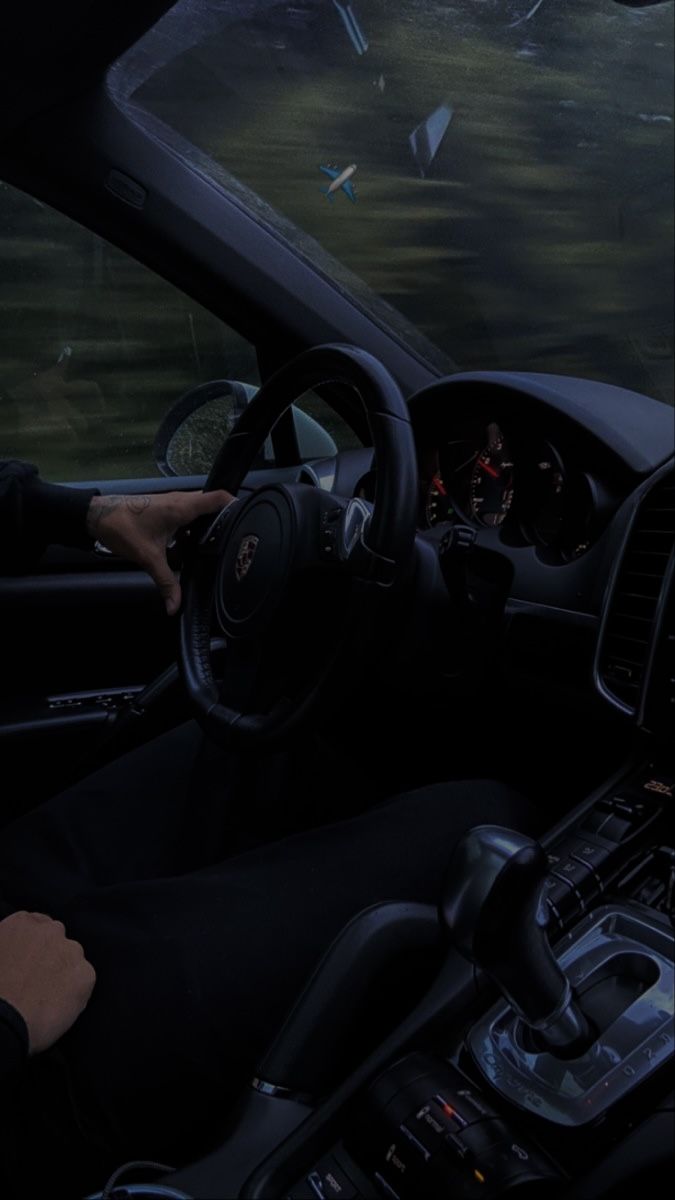 a man driving a car in the rain with his hands on the steering wheel and dashboard