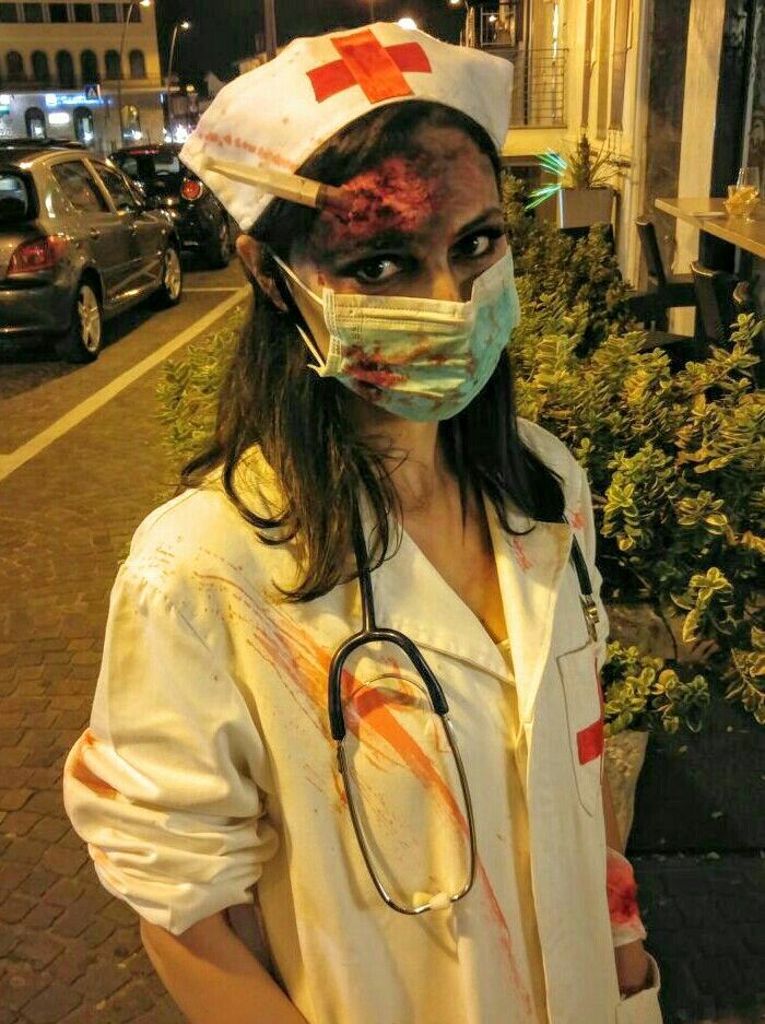 a woman wearing a medical mask with blood on her face and stethoscope around her neck