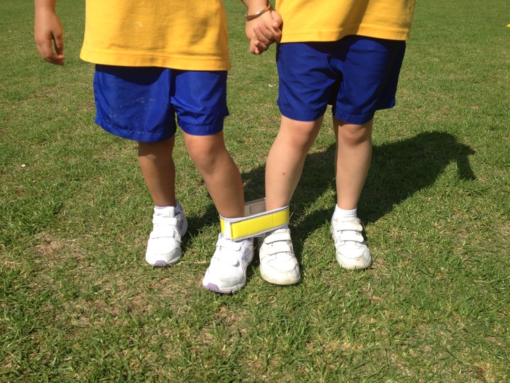 two young boys holding hands while standing on top of a grass covered field in yellow and blue uniforms