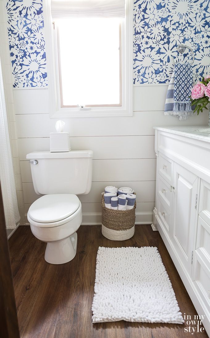 a white toilet sitting in a bathroom next to a window with blue and white wallpaper